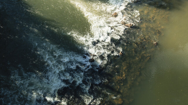 Aerial view of the Sava river rapids flowing over rocks with white foam and sunlight reflecting on the water near Pot Na Debni Vrh Ljubljana, Ljubljana, Slovenia.