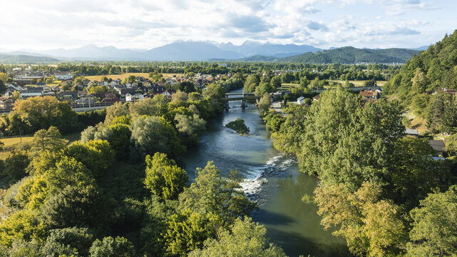 Aerial view of the winding river flowing through lush green forests and residential areas with the Kamnik-Savinja Alps in the background Ljubljana, Ljubljana, Slovenia.