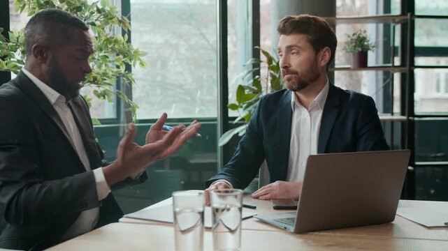 Two diverse business men team multiracial businessmen emotional talking discuss problem negotiation stress job partnership in office discussing ideas difficulties laptop project complaint deal working