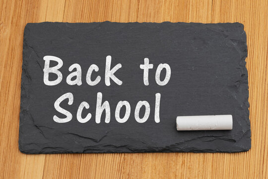 Back to School text on chalkboard with a piece of chalk on a wood desk
