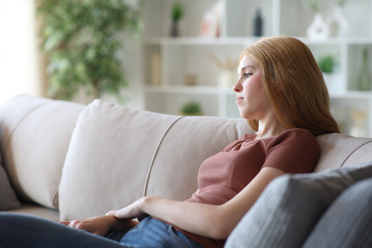 Apathetic young woman looking away on a couch