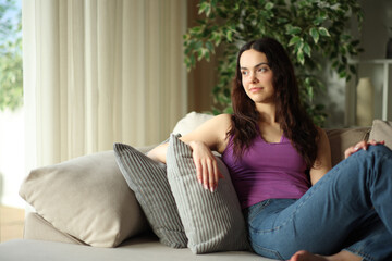 Obraz premium Relaxed young woman thinking at home contemplating through a window