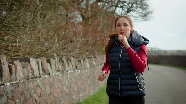 Energetic woman performing sport walking on rural pathway. Calorie burning workout strengthening lungs and boosting blood circulation. Healthy cardio routine promoting stamina and weight management