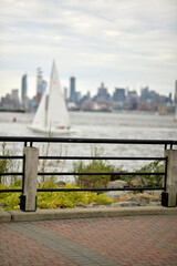 Obraz premium Small Sailboat Moves Smoothly Over Surface Of Water With Highrise Buildings In Background new york
