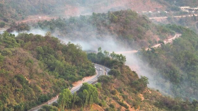 Drone shot of wildfire smoke over national highway in India. Climate change disaster due to Global Warming
