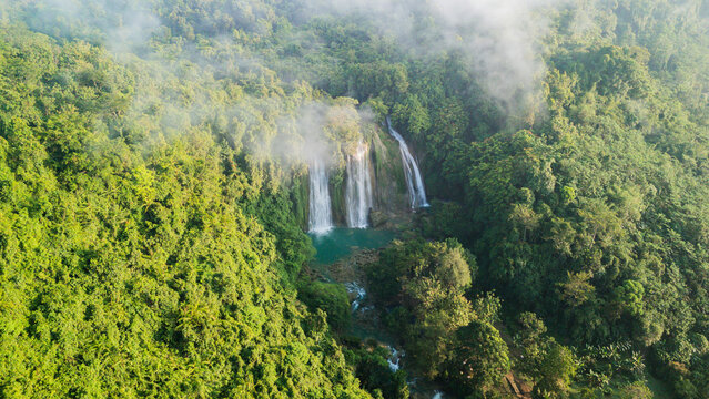 Aerial view of Cikaso Waterfall cascading into a turquoise pool surrounded by dense tropical jungle and morning mist Sukabumi, West Java, Indonesia.