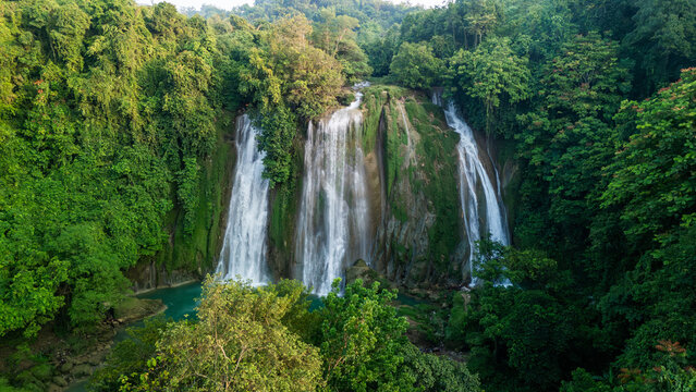 Aerial view of Cikaso Waterfall with three powerful cascades falling into a turquoise pool surrounded by lush tropical jungle Sukabumi, West Java, Indonesia.