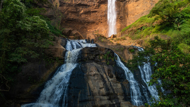 Aerial view of Cikanteh Waterfall cascading over dark rocky cliffs surrounded by dense tropical forest and lush greenery in Sukabumi, West Java, Indonesia.