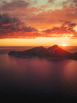 Aerial view of Sa Dragonera island at sunset with vibrant orange clouds over the Mediterranean Sea Sant Elm, Balearic Islands, Spain.