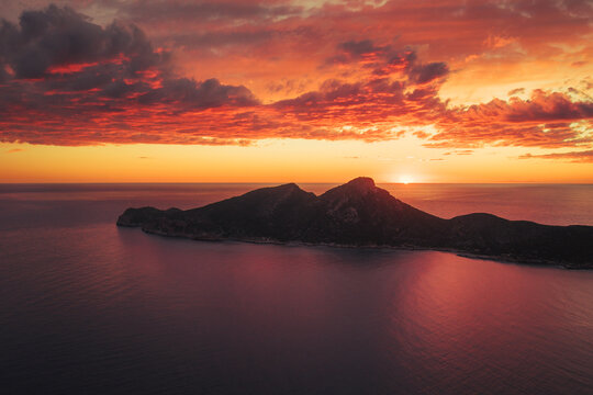 Aerial view of Sa Dragonera island silhouette under a vibrant sunset sky with orange and red clouds over the Mediterranean Sea Sant Elm, Balearic Islands, Spain.