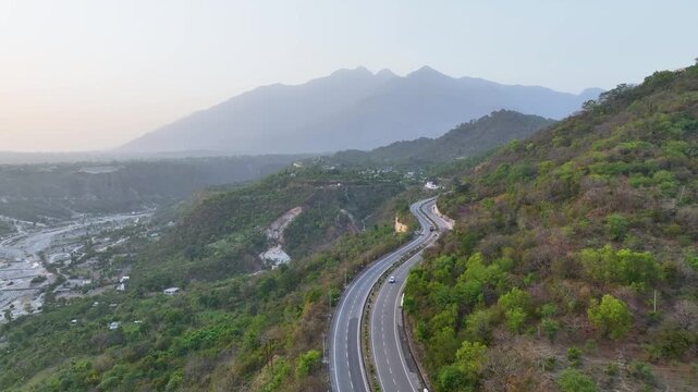 Drone shot of mountain road and Trikuta hills. In the background, the majestic, hazy peaks of the Trikuta Hills&mdash;home to the holy Mata Vaishno Devi shrine.