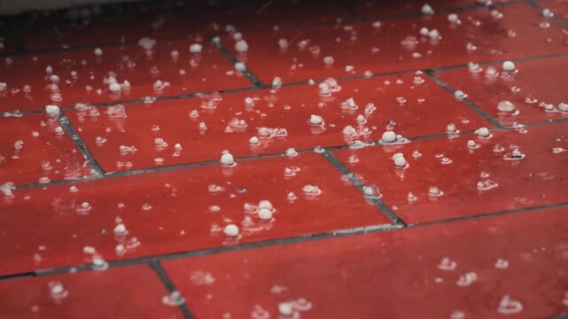 Close-up of hail falling onto a red tiled balcony or terrace during a storm. Extreme weather, cyclone and heavy precipitation concept. High quality 4k footage