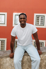 Fototapeta premium Young black man smiling outdoors, red building background