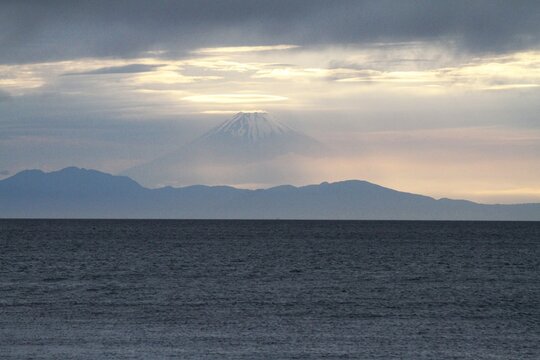 Ethereal view of Mount Fuji emerging through twilight clouds over Tateyama bay.