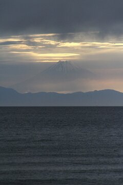 Mystical Mount Fuji emerging through twilight clouds over Tateyama bay in spring.