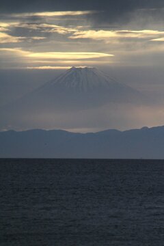春の霞の中にそびえ立つ夕暮れの富士山の雄大なシルエット（縦位置）