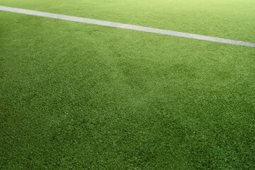 Obraz premium Texture background of a vibrant green synthetic turf field with a diagonal white line, ideal for sports and fitness concepts