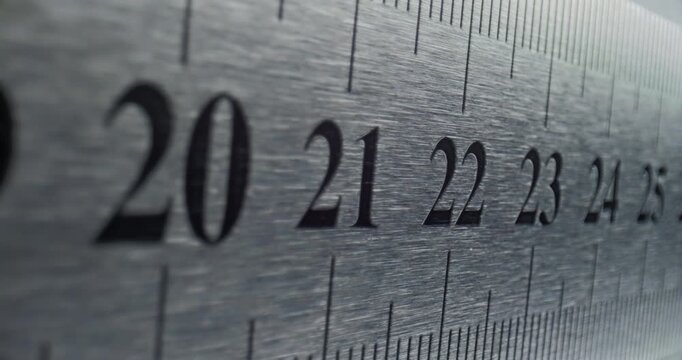 Close-up of a Metal Ruler Showing Measurement in a Professional Setting.  Smooth slow movement across extreme close-up of metallic ruler with black numbers and brushed surface.	