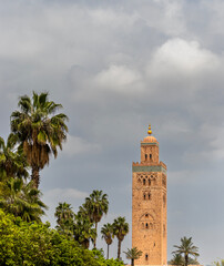 Fototapeta premium Koutoubia Mosque Minaret Tower with Palm Trees under Cloudy Sky in Marrakech Morocco