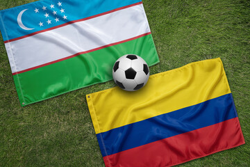 Fototapeta premium Uzbekistan and Colombia flags with a soccer ball on a green grass field a patriotic sports composition national football equipment nationalism international
