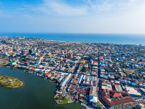 Aerial view of the dense urban landscape of the city with colorful rooftops along the riverbank under a clear blue sky in Monrovia, Liberia.