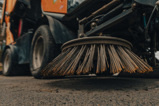 Street sweeper brush cleaning asphalt surface on municipal vehicle