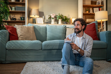 Man thinking and writing ideas at home © Migma_Agency