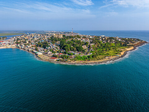 Aerial view of the coastal city of Monrovia with urban buildings and lush greenery along the Atlantic Ocean shoreline in Monrovia, Liberia.