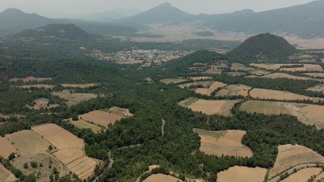 A camera tilt reveals agricultural patchwork fields leading to town and distant peaks.