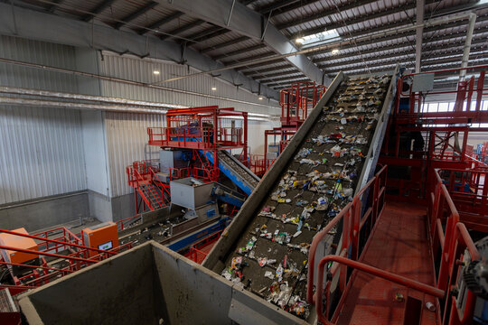 Waste sorting facility interior with conveyor belts and mixed garbage in recycling plant