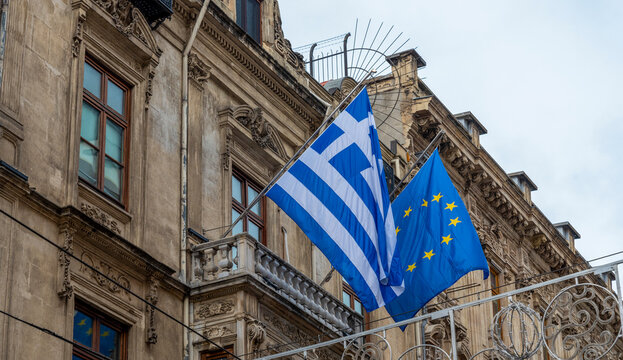 The flags of Greece and the European Union, hanging from a building in Istanbul on a cloudy day