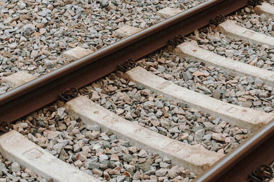 Detailed view of railway track with gravel and concrete sleepers. Concept of transportation infrastructure logistics and industrial mobility.