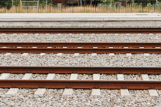 Parallel railway tracks near station platform in outdoor environment. Concept of public transport logistics travel and industrial infrastructure.