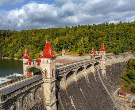 Aerial view of the Royal Forest Dam featuring its iconic stone arches and red-roofed towers surrounded by lush autumn forests in Bila Tremesna, Hradec Kralove Region, Czechia.