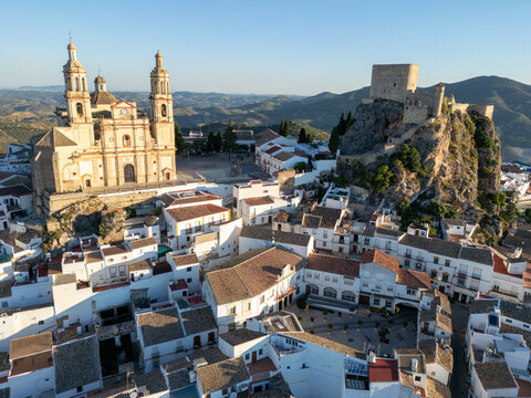 Aerial view of the Parish Church of Nuestra Senora de la Encarnacion and the medieval castle overlooking white houses and rolling hills in Olvera, Andalusia, Spain.