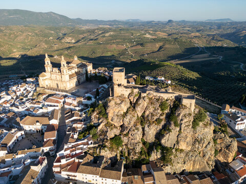 Aerial view of the historic Castle of Olvera and the Parish Church of Nuestra Senora de la Encarnacion overlooking white houses and rolling hills in Olvera, Andalusia, Spain.