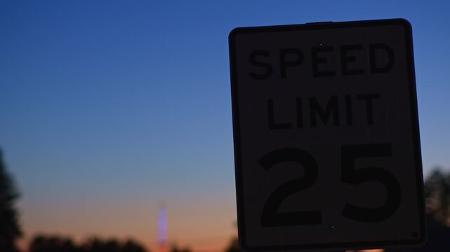 Speed limit sign against colorful twilight evening sky standing along a street at dusk creating a recognizable scene of urban environment and transportation infrastructure