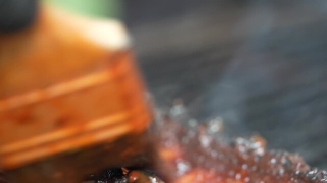 A chef grills ribs on a large BBQ grill outdoors.
