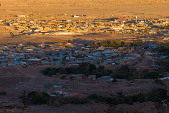 Aerial view of the historic town of San Pedro de Atacama with its low-rise buildings and arid landscape under the warm glow of sunset in San Pedro de Atacama, Antofagasta, Chile.