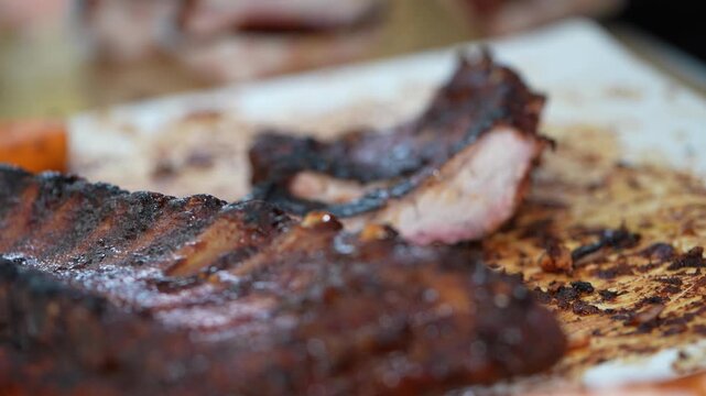 A chef grills ribs on a large BBQ grill outdoors.

