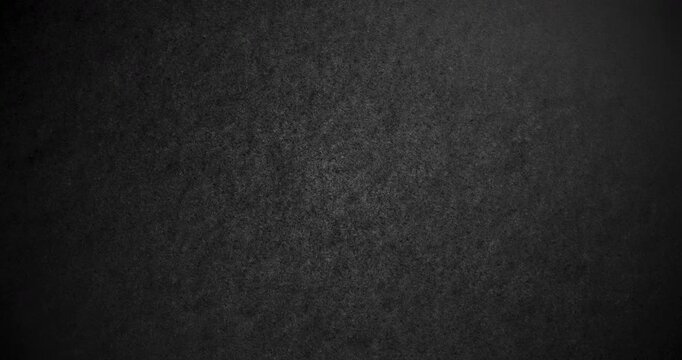 Dark Rough Texture Loop. Subtle continuous movement across a deep black rough textured surface with fine grain and soft light gradients. 