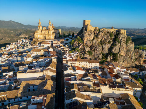 Aerial view of the historic Olvera Castle and the Parish of Our Lady of the Incarnation perched on a rocky hill above white-washed houses Olvera, Andalusia, Spain.