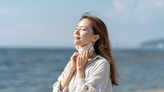 Freedom Found: A woman on a sun-drenched beach exhales in relief, tossing aside her face mask and embracing the refreshing ocean breeze. A symbol of hope and return to normalcy.