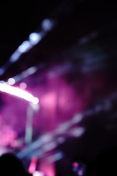 Abstract colorful concert bokeh background with blurred stage lights and glowing pink light stick silhouette, creating an energetic nightlife and live music atmosphere with soft defocused illumination