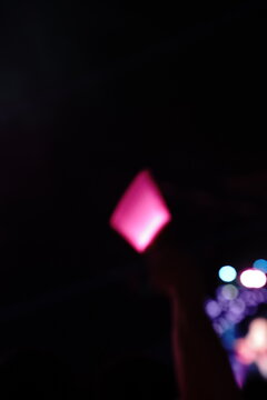 Abstract colorful concert bokeh background with blurred stage lights and glowing pink light stick silhouette, creating an energetic nightlife and live music atmosphere with soft defocused illumination