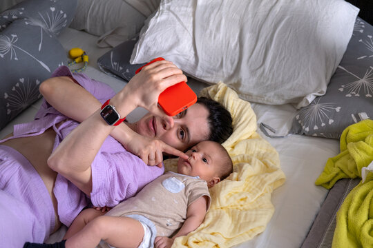 Mother and newborn baby taking selfie in bed overhead