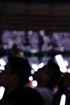 Abstract colorful concert bokeh background with blurred stage lights and glowing pink light stick silhouette, creating an energetic nightlife and live music atmosphere with soft defocused illumination