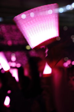 Abstract colorful concert bokeh background with blurred stage lights and glowing pink light stick silhouette, creating an energetic nightlife and live music atmosphere with soft defocused illumination