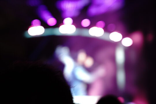 Abstract colorful concert bokeh background with blurred stage lights and glowing pink light stick silhouette, creating an energetic nightlife and live music atmosphere with soft defocused illumination