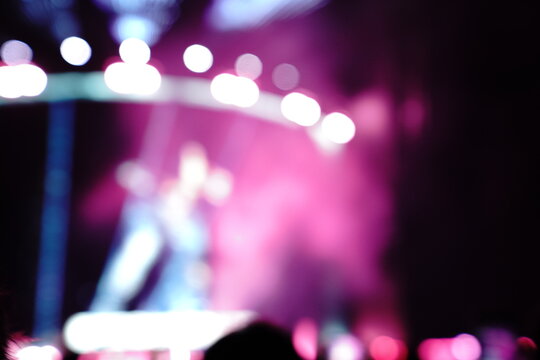 Abstract colorful concert bokeh background with blurred stage lights and glowing pink light stick silhouette, creating an energetic nightlife and live music atmosphere with soft defocused illumination